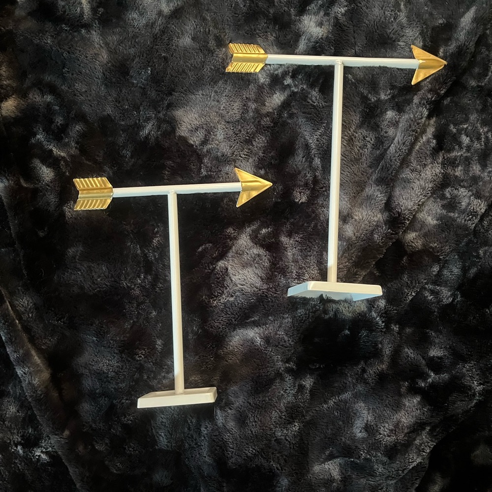 Pair of white and gold arrow shaped jewelry stands with base tray.